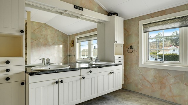 Badet har fliser på gulvet og godt med dagslys fra vinduene.