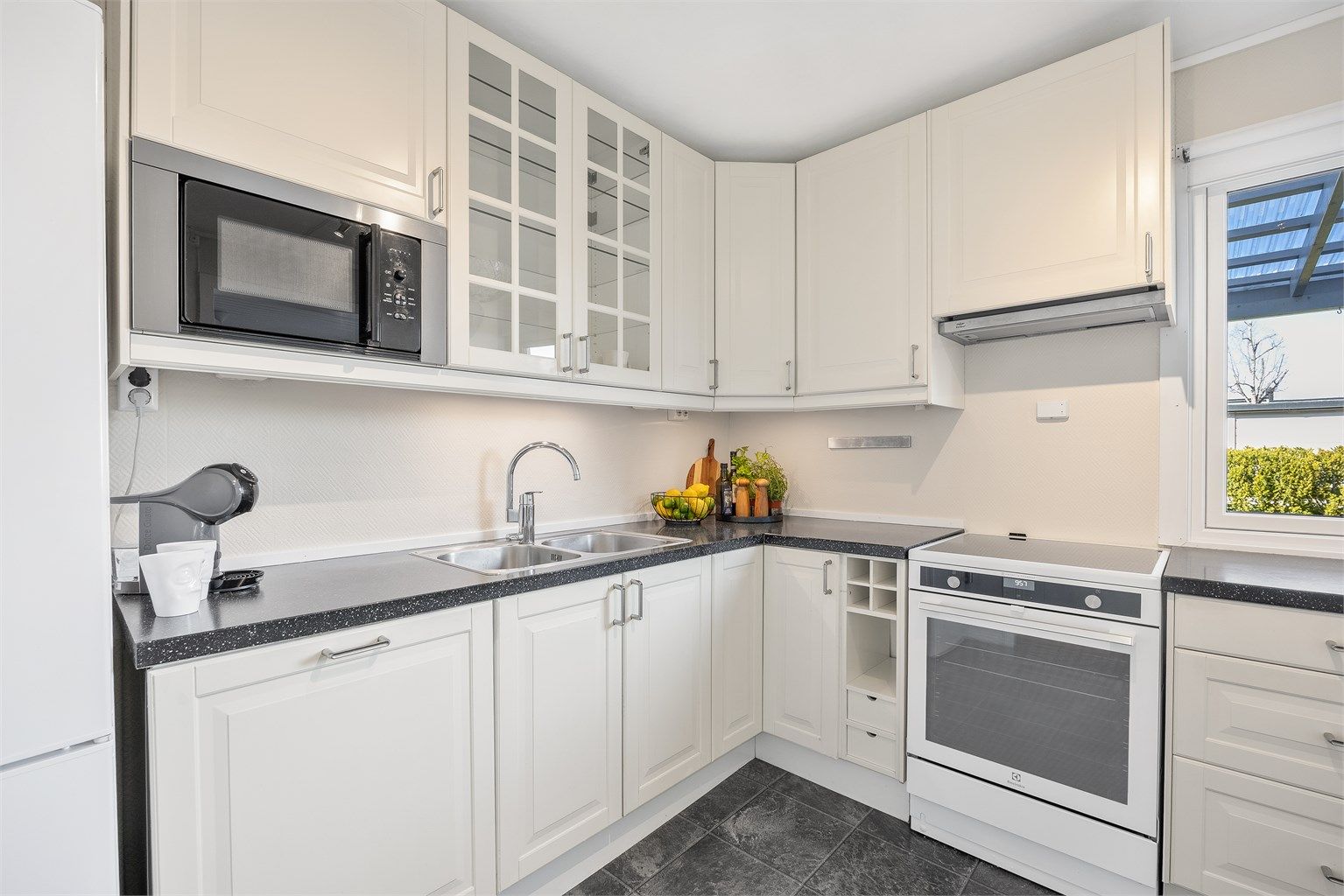 Detaljer som vitrineskap og en egen hylle for vinflasker gir kjøkkeninnredningen karakter.