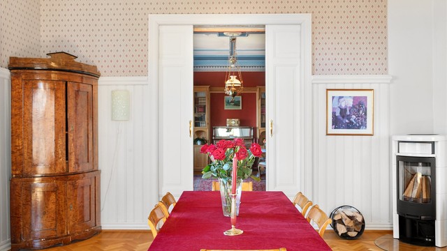 En vedfyrt peisovn gir varme, og profilerte skyvedører åpner inn til stuen