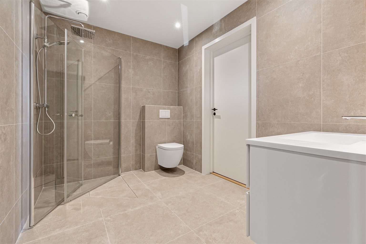 Badene er utstyrt med vegghengt toalett, servant og innfelte glassdører til dusj. Bad første etasje