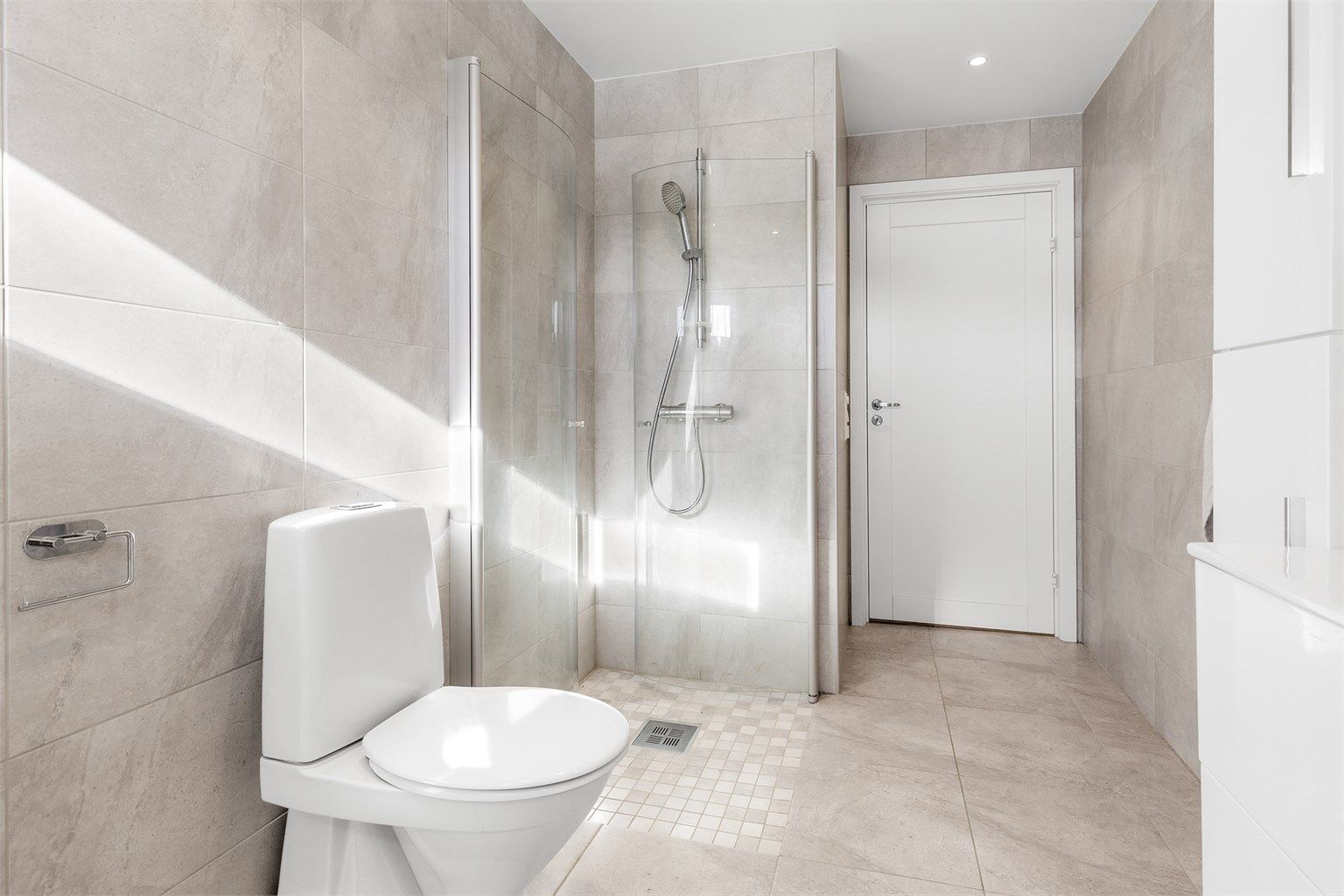 Badet har dusjhjørne med foldedører av glass