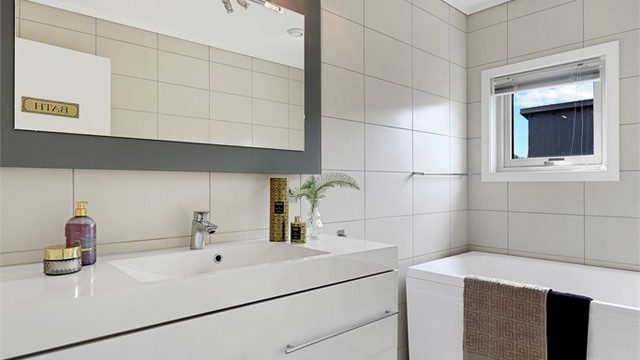Badet i andre etasje er utstyrt med badekar og servant i innredning.
