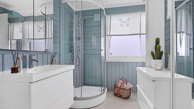 Badet er innredet med gulvmontert toalett, badekar, baderomsinnredning med nedfelt vask og dusjkabinett.