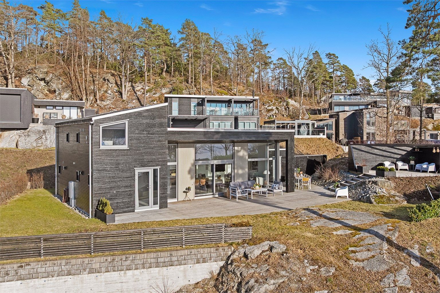 De store vindusflatene har karmer av aluminium. Uteplassen har terrassebord i grove dimensjoner og er rundt 125 kvm.