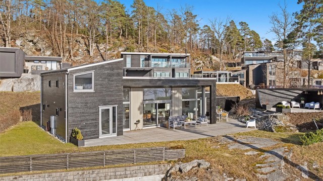 De store vindusflatene har karmer av aluminium. Uteplassen har terrassebord i grove dimensjoner og er rundt 125 kvm.