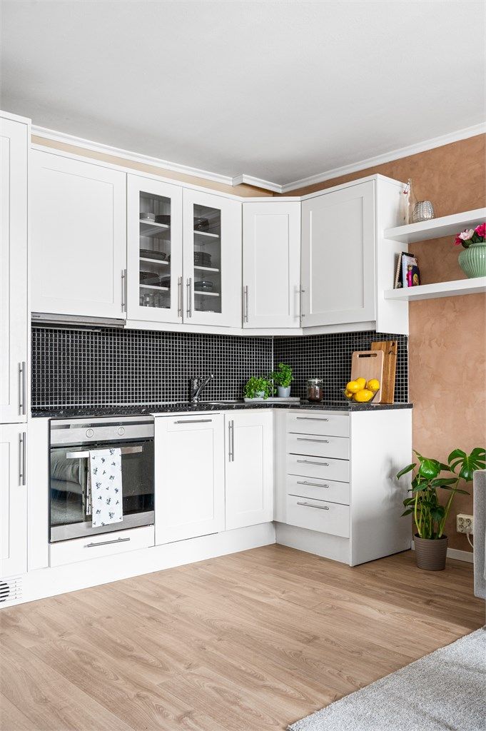 Kjøkkeninnredning med profilerte fronter, laminatbenkeplate og integrerte hvitevarer.