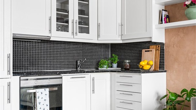 Kjøkkeninnredning med profilerte fronter, laminatbenkeplate og integrerte hvitevarer.