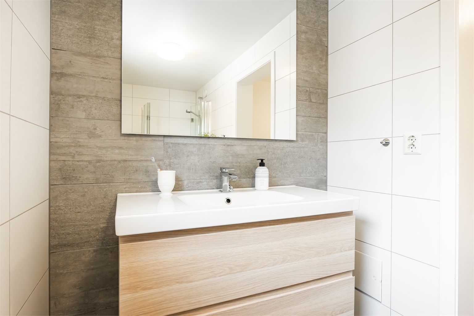  Innredningen har glatte fronter og heldekkende servant med ett-greps armatur, speil og stikkontakter.