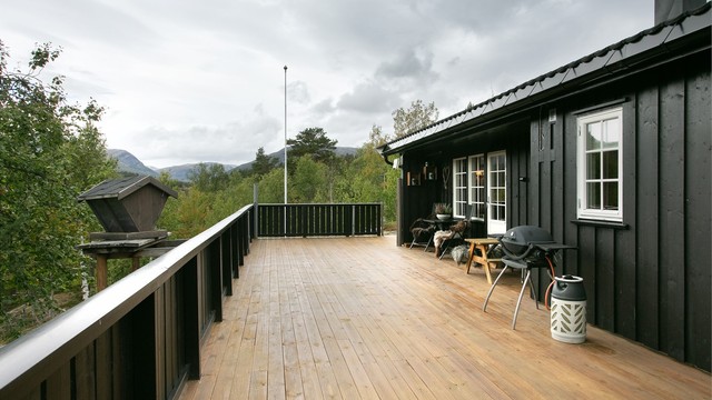 Langstrakt terrasse med rekkverk og god plass til utegrill og sittegrupper.