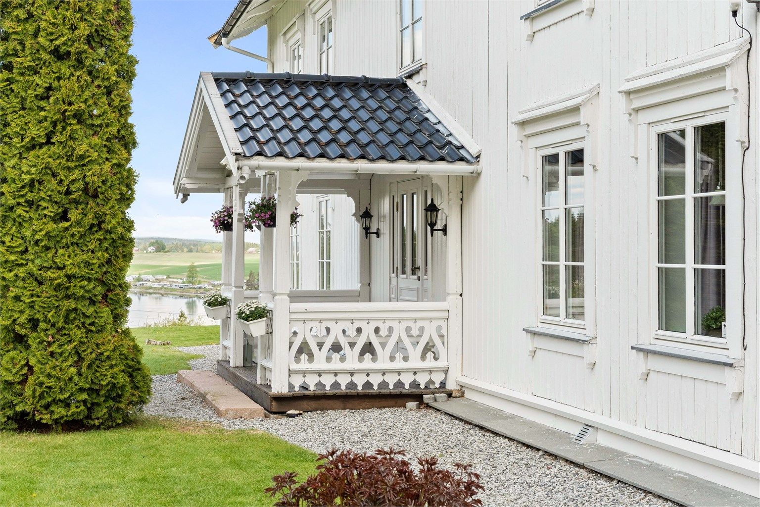 Overbygget inngangsparti med profilerte stolper og dekorativt rekkverk.