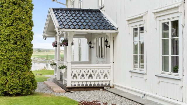 Overbygget inngangsparti med profilerte stolper og dekorativt rekkverk.
