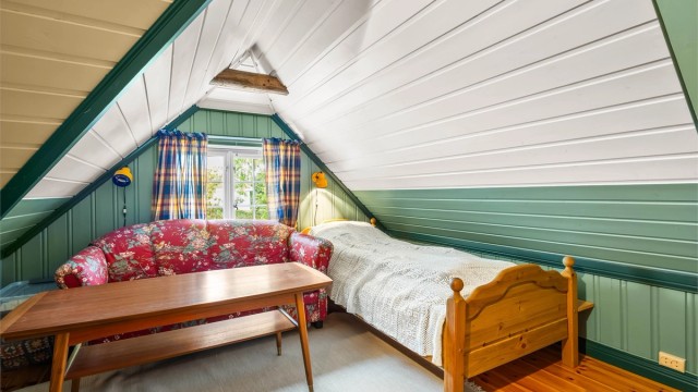 Innredet rom på loftet i 'Skålen', med panel på vegger og i skråtak.