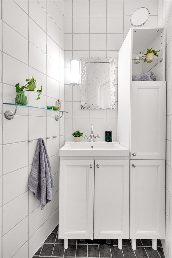 Badet er innredet med gulvstående servantinnredning med ovenpåliggende vask. Over vasken er det speil og lys. Det er også et gulvstående høyskap på badet som bidrar til ekstra oppbevaring.