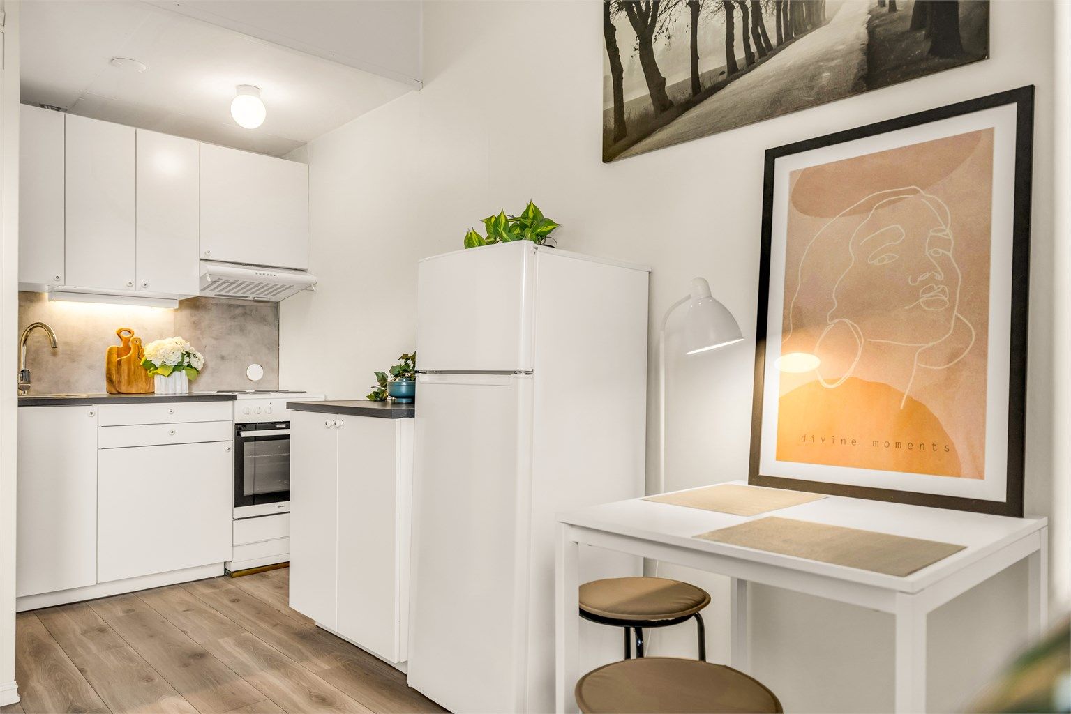 Kjøkken med moderne innredning fra 2020 med glatte fronter, benkeplate av laminat og nedfelt kjøkkenvask med armatur. Det er montert benkeskapsbelysning og stikkontakter under kjøkkenbenken. 