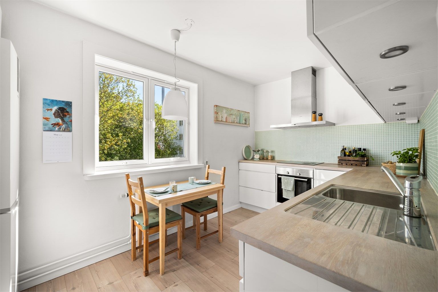 Kjøkkenet har benkeplate i tre som gir varme til rommet og står fint til de lyse flatene og den delikate mosaikkflisen mellom benk og overskap.