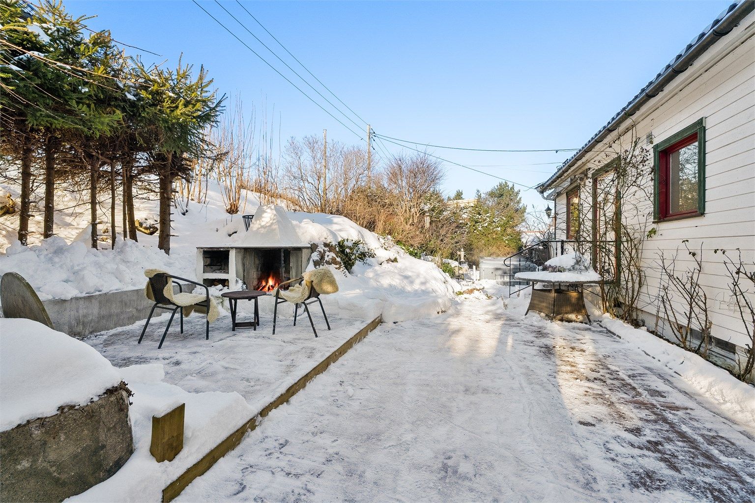 Flott uteplass på terrasseplatting med peis. God plass til utemøbler