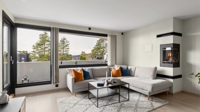 Stuen har god plass til stor sofagruppe. Den moderne peisinnsatsen er både praktisk og et blikkfang