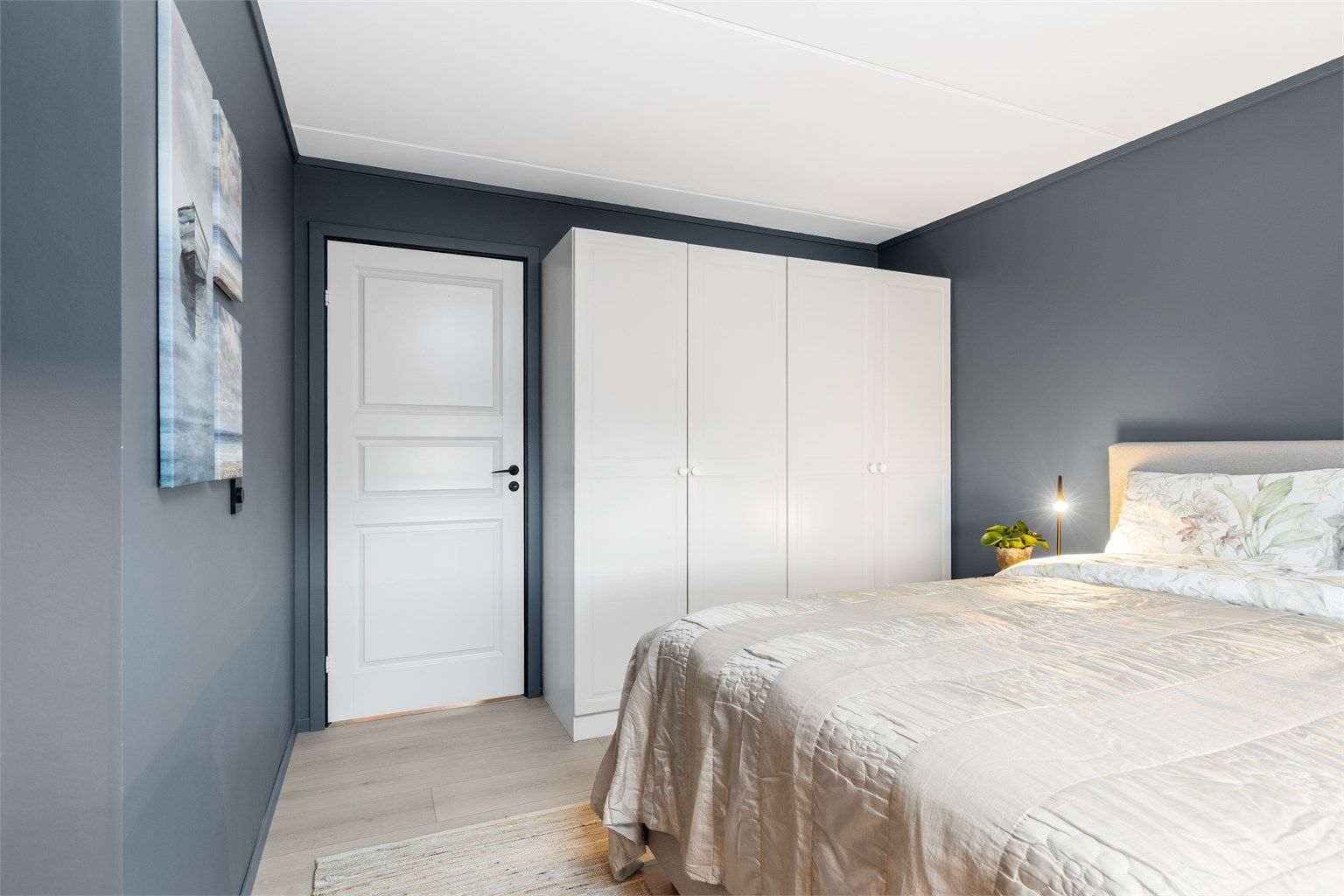 En stor garderobeløsning med hvite, glatte fronter gir rikelig med oppbevaringsplass.