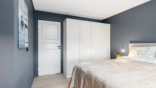 En stor garderobeløsning med hvite, glatte fronter gir rikelig med oppbevaringsplass.