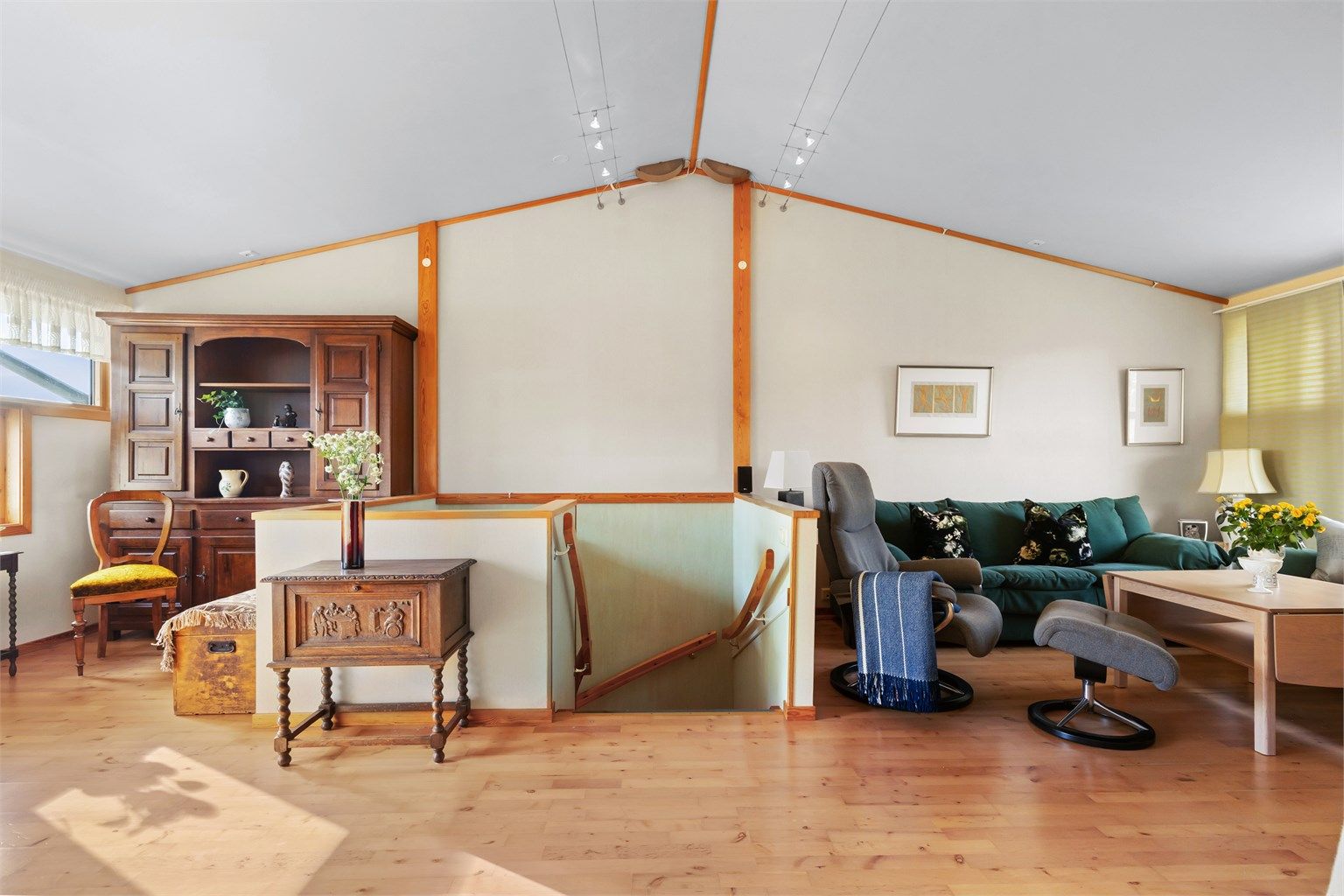 Gjennomgående parkett og lyse, tapetserte vegger gir et helhetlig inntrykk i stuens oppholdsdel.