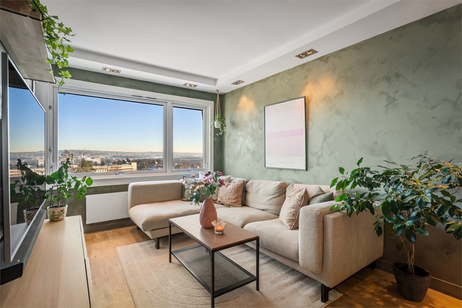 Stuen har god plass til både sofagruppe, spisebord og vitrineskap. Flott utsikt utover Oslo by og fjord