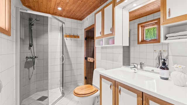 Badet i andre etasje har flislagt gulv med gulvvarme og dusjnisje med glassdører.