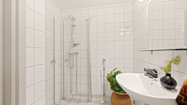 Praktisk innredning med servant, speil, toalett og dusjhjørne med svingbare, plassbesparende glassdører