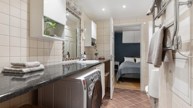 Badet har fliser på gulv med gulvvarme, fliser på vegger og malt himling med downlights