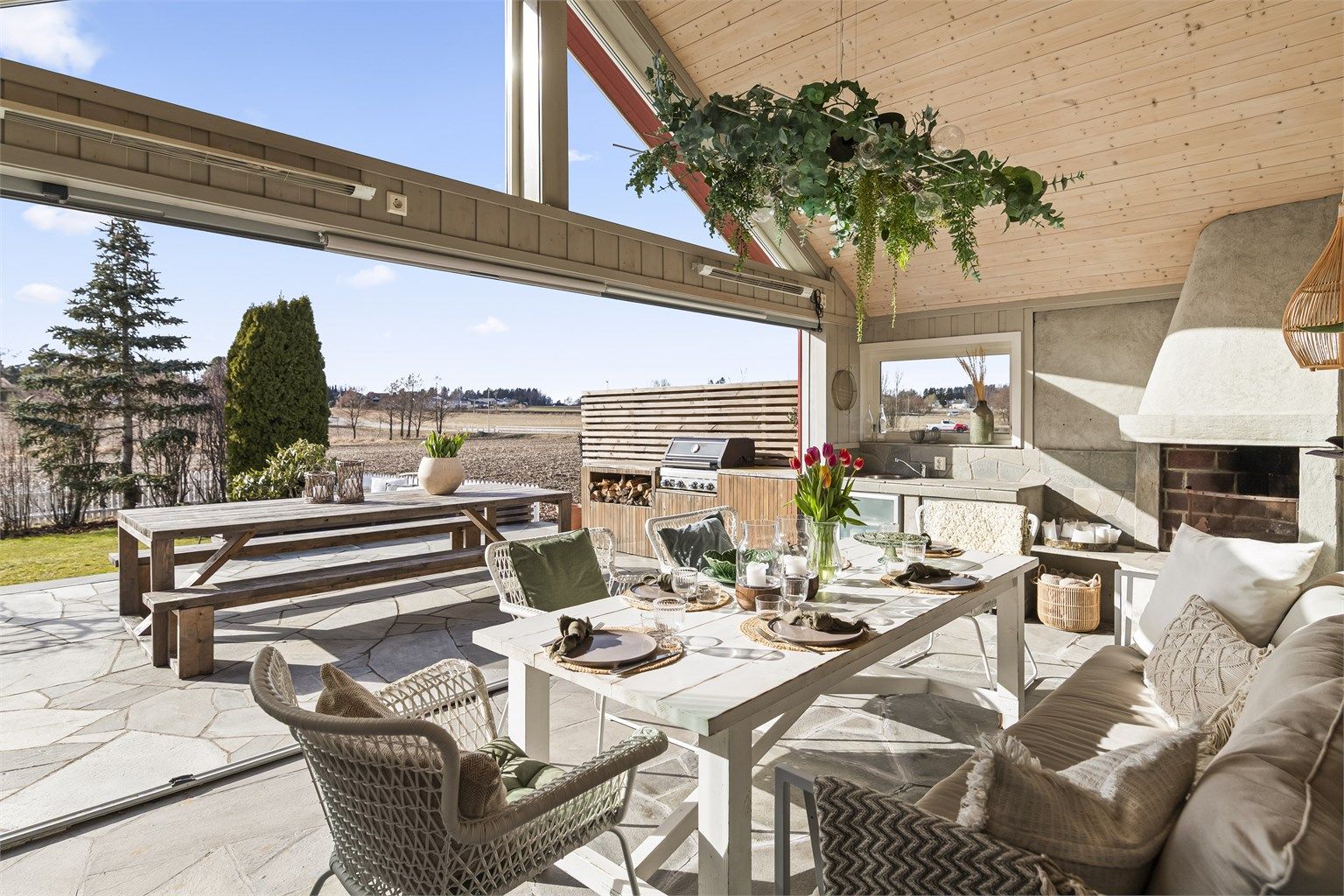 Rommet åpner seg fullstendig mot den 44 m² store, skiferbelagte uteplassen.