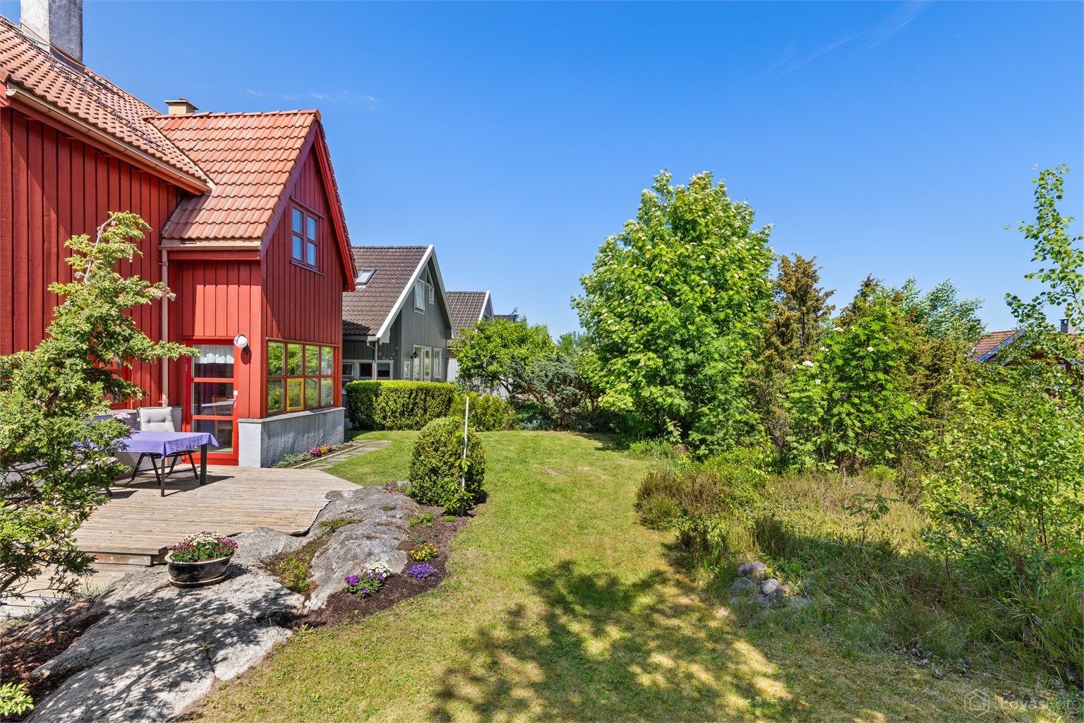 Tomten er opparbeidet med plenarealer, beplantning og naturlig fjell i dagen.