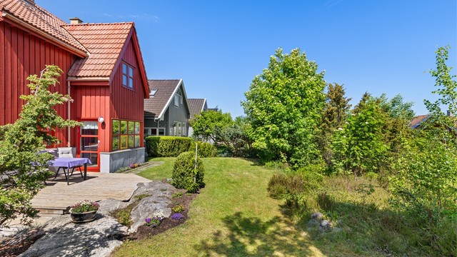 Tomten er opparbeidet med plenarealer, beplantning og naturlig fjell i dagen.