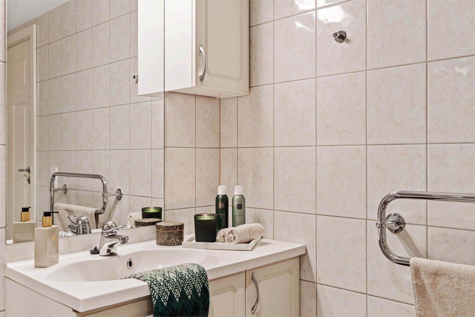 Badet har en stilren servantinnredning fra Norema og flislagte overflater.