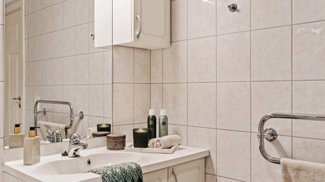 Badet har en stilren servantinnredning fra Norema og flislagte overflater.