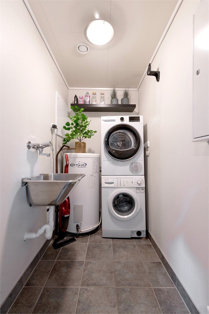 Separat vaskerom med flislagt gulv, gulvvarme og opplegg for vaskemaskin. Her er også boligens varmtvannsbereder plassert.