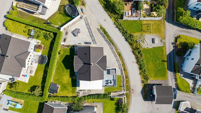 Tomten er opparbeidet i to nivåer med plenarealer, terrasser og gode parkeringsforhold.