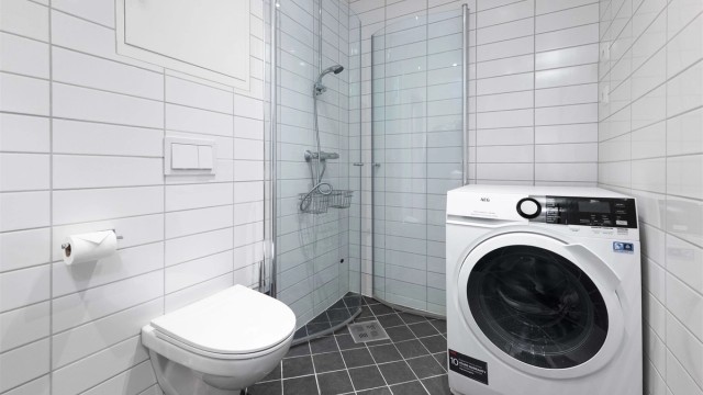 Pent flislagt bad med god plass til vaskemaskin i rommet.