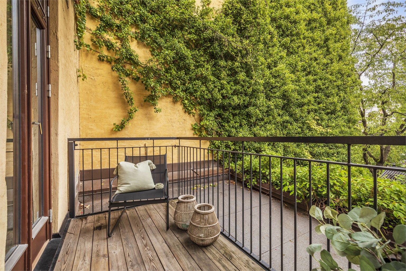 Balkongen er skjermet med en frodig vegg på ene siden, som gir en lun atmosfære