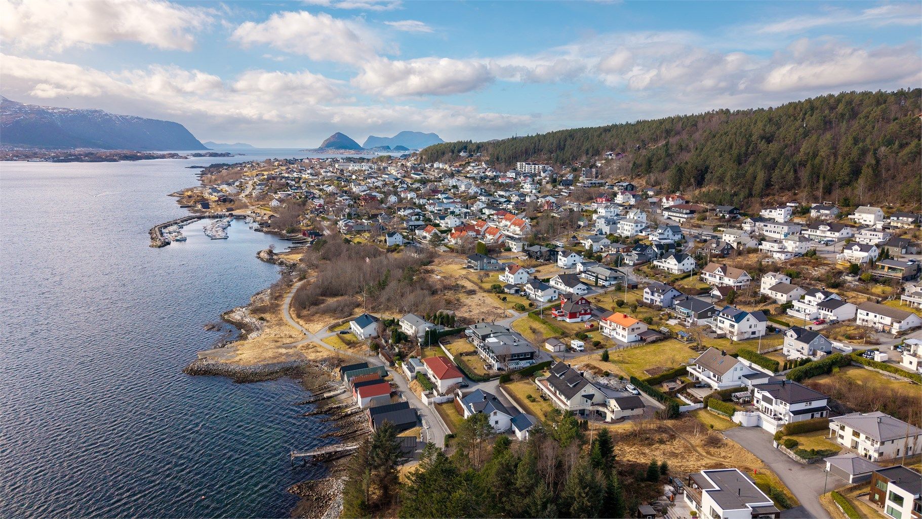 Dronebilde over boligområde og naustrekken på Åsestranda - tatt fra øst mot vest