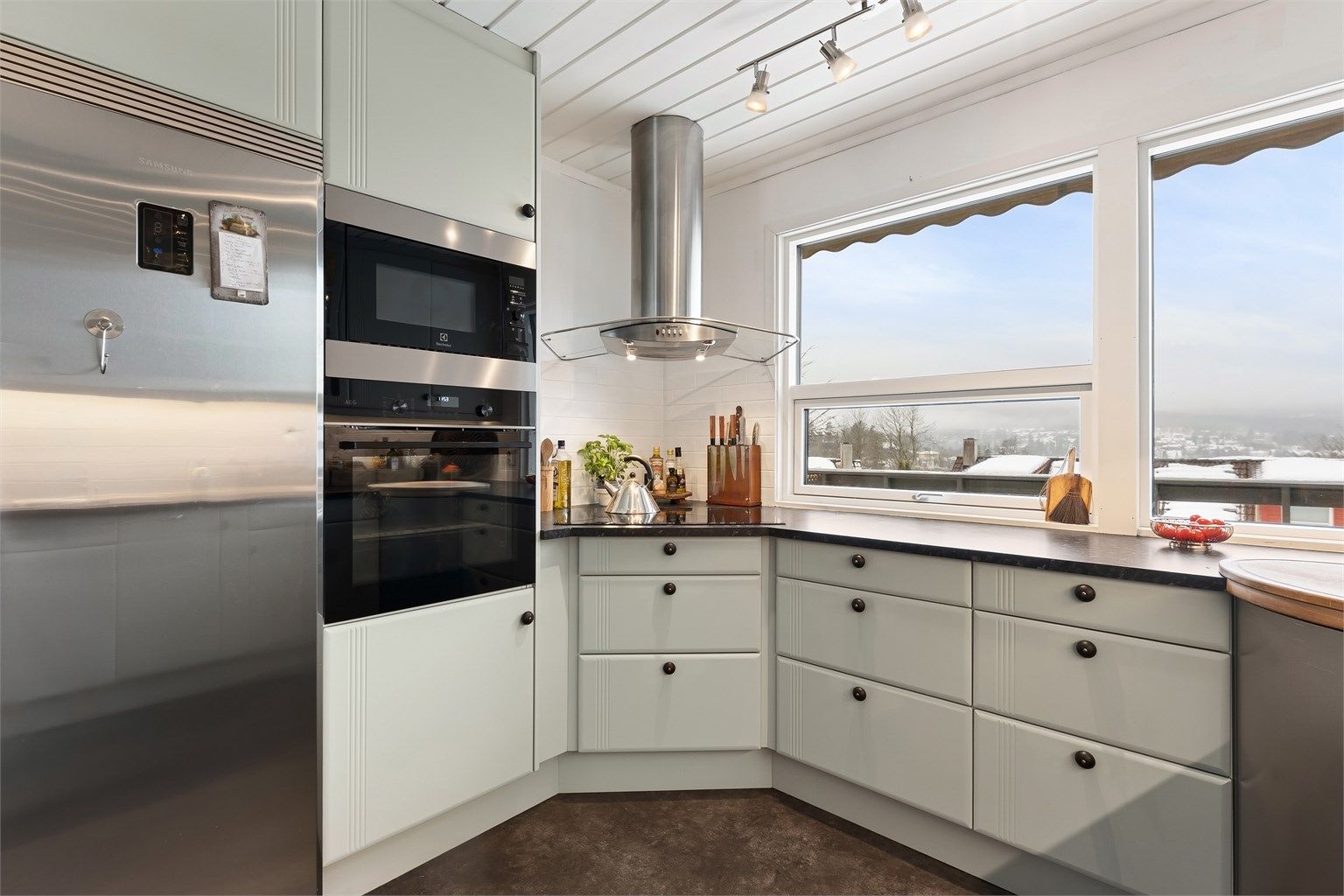 Stilrent kjøkken med integrert platetopp, stekeovn, mikrobølgeovn og oppvaskmaskin, samt plass for frittstående kjøleskap