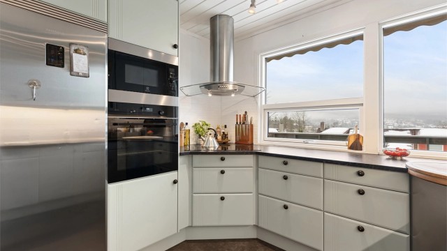 Stilrent kjøkken med integrert platetopp, stekeovn, mikrobølgeovn og oppvaskmaskin, samt plass for frittstående kjøleskap