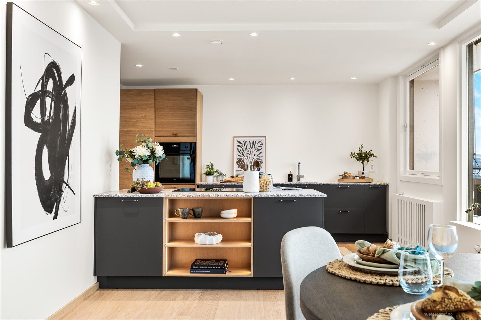 Kjøkkenhalvøya fungerer som en naturlig romdeler med praktisk oppbevaring og ekstra arbeidsflate.