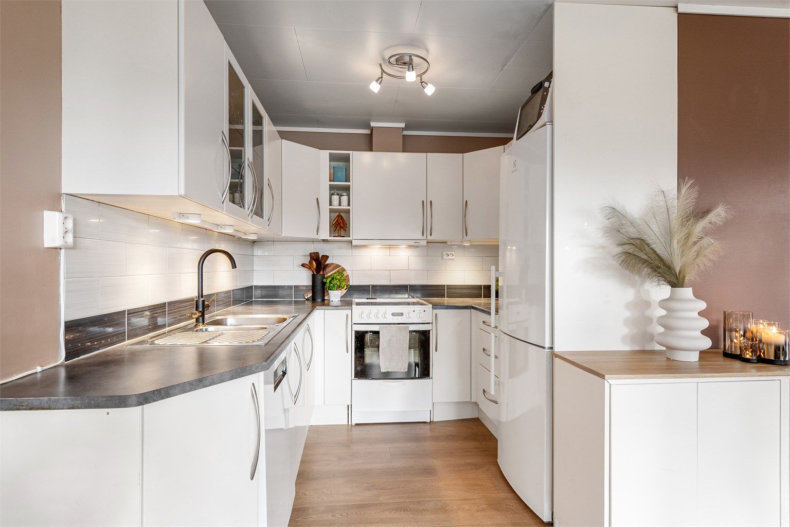 Kjøkkeninnredning fra Sigdal med glatte fronter og laminat benkeplate. Frittstående hvitevarer medfølger.