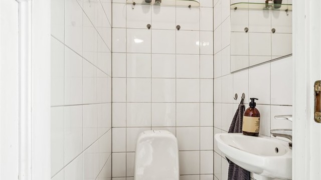 Vegg i vegg med baderommet finner du boligens toalettrom med gulvstående toalett og vegghengt servant.