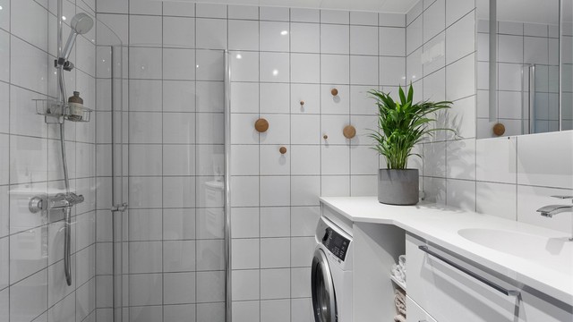 Flislagt bad med behagelig gulvvarme, dusjhjørne med innfellbare dører og opplegg for vaskemaskin.
