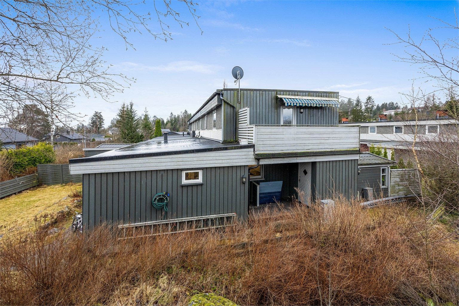 Fasaden er kledd med en kombinasjon av liggende og stående trekledning og synlig murverk.