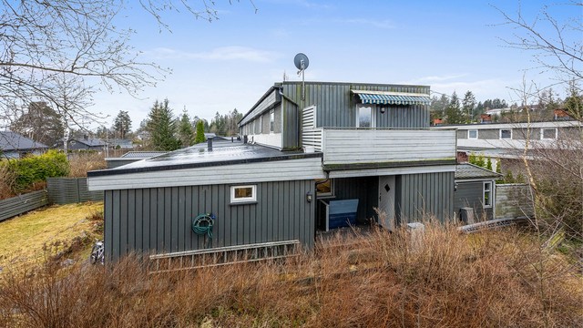 Fasaden er kledd med en kombinasjon av liggende og stående trekledning og synlig murverk.