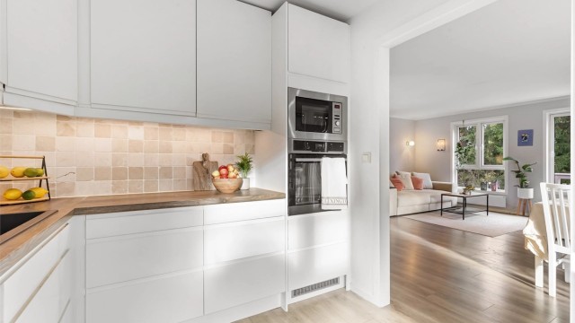 Kjøkkenet har slette fronter på skap og skuffer, benkeplate av laminat med nedfelt oppvaskkum, integrert platetopp, stekeovn, mikrobølgeovn, kjøleskap og oppvaskmaskin