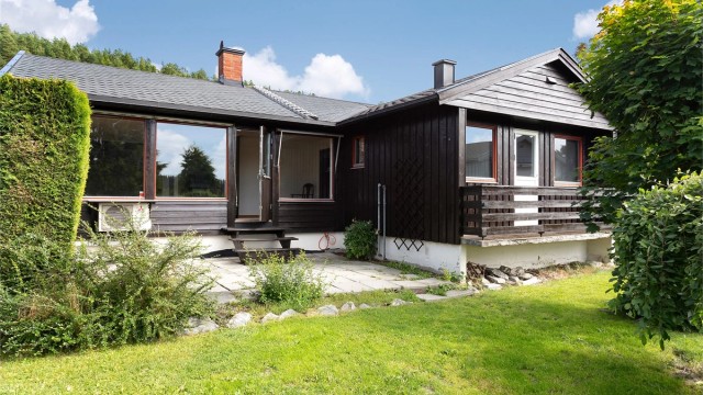 Steinlagt uteplass på terreng med utgang fra stuen.