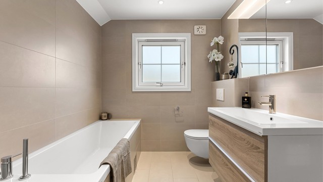 Pent baderom fra 2020 med fliser på gulv med gulvvarme, fliser på vegger og malt himling med downlights