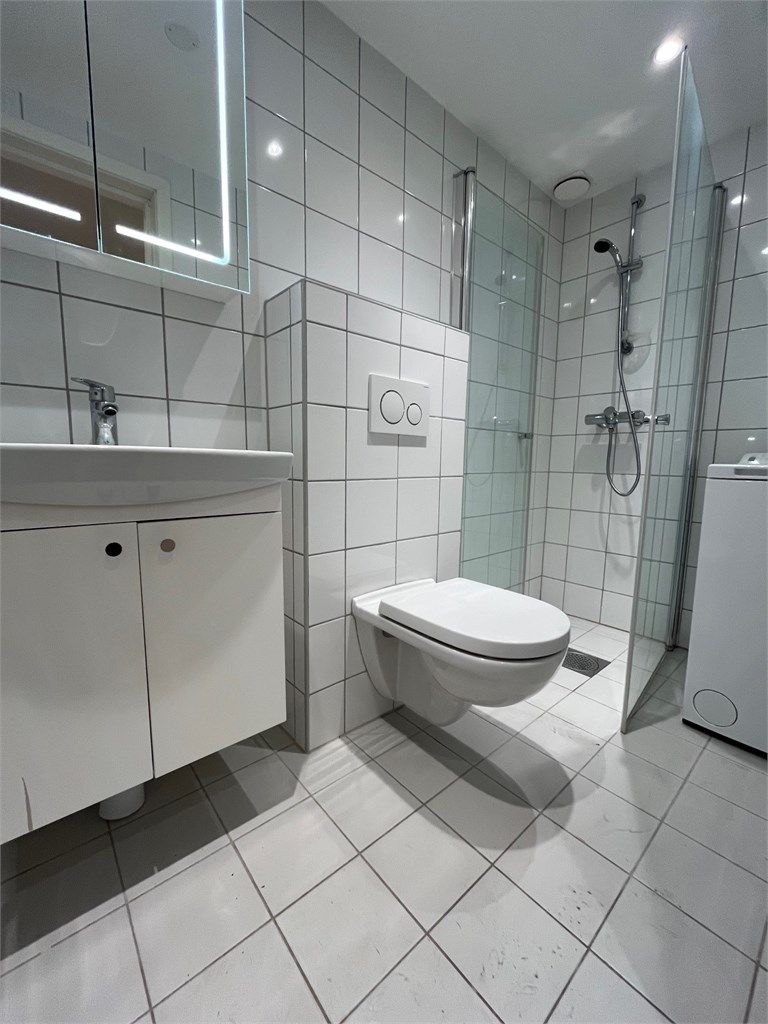 Pent flislagt baderom med vaskemaskin. 